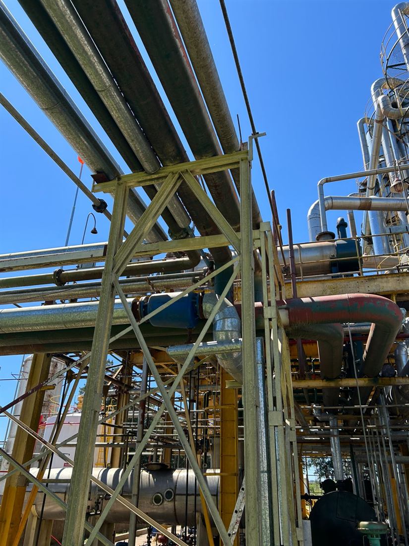 Pipe rack y torre de destilación en planta de proceso